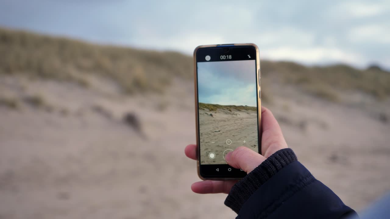 primer plano de una mujer joven haciendo un video con un teléfono inteligente en un día soleado en la hermosa playa de sylt