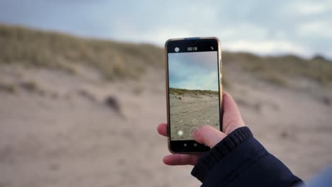 Close-up-of-a-young-woman-making-a-video-with-a-smartphone-on-a-sunny-day-at-the-beautif-beach-of-Sylt