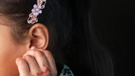 close up of a young girl's ear with a flower hair clip