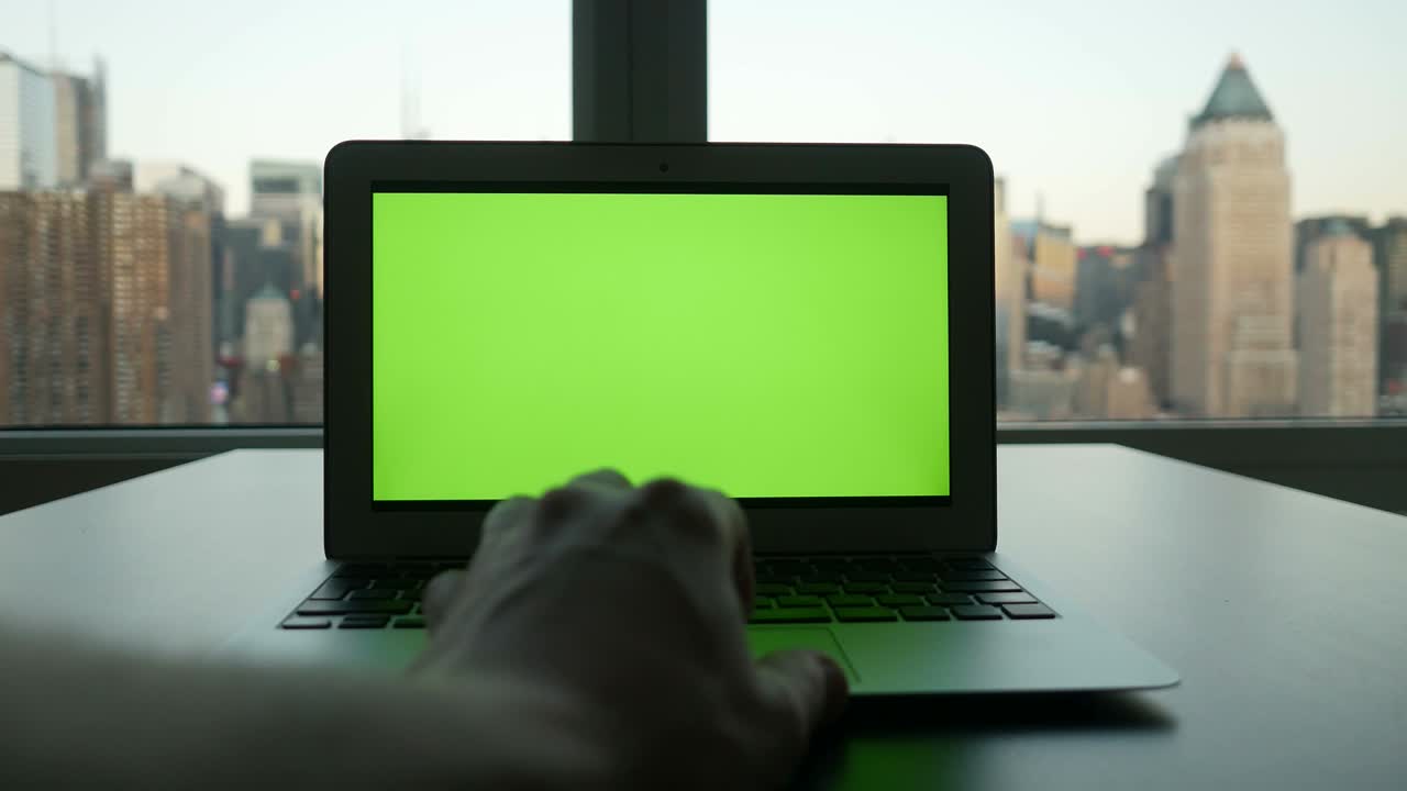 laptop de negócios com ecrã verde, monitor de chave de croma e fundo de paisagem urbana.