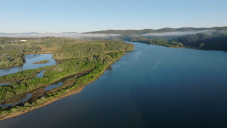 Aerial: drone flying up the Bega river with low lying patches of cloud still visible during the early morning