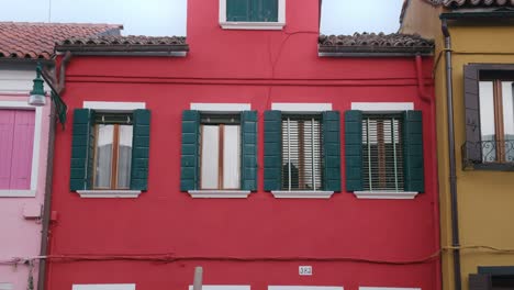 Colorful-houses-of-Burano-Island-with-green-shutters-and-windows,-bright-and-vibrant-facade