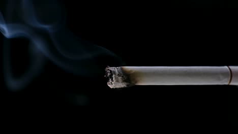 Spitze-Einer-Zigarette,-Die-Sich-Langsam-Verzehrt-Und-Dabei-Eine-Rauchfahne-Ausstößt,-Vor-Schwarzem-Hintergrund