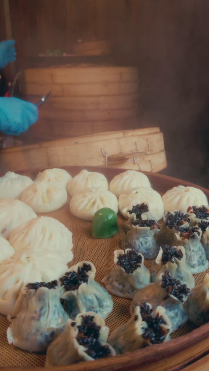 Steaming dumplings in a bamboo basket, a cook handles them in Wuzhen, China