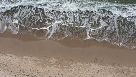 aerial view of sea waves rolling on a sandy beach in clear weather