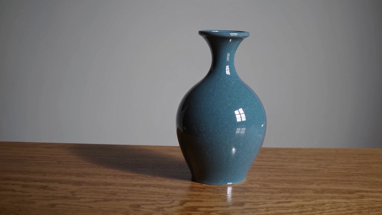 Elegant blågrønn keramikkvase på et trebord