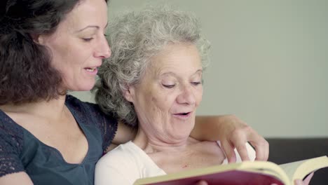 Daughter-and-mother-reading-book,-discussing,-laughing