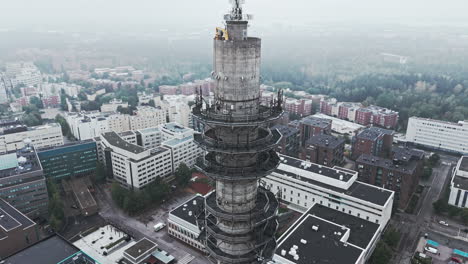 Toma-Aérea-De-Una-Sombría-Torre-De-Enlace-De-Radio-Y-Televisión-De-Hormigón-Industrial-En-Pasila,-Helsinki,-Finlandia,-En-Un-Día-Brillante-Y-Brumoso