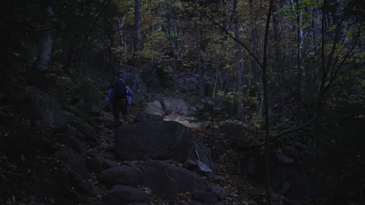 손전등으로 어둠 속에서 가파른 바위 길을 하이킹하는 청년
