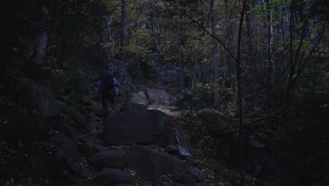 young man hiking up a steep rocky trail in the dark with a flashlight