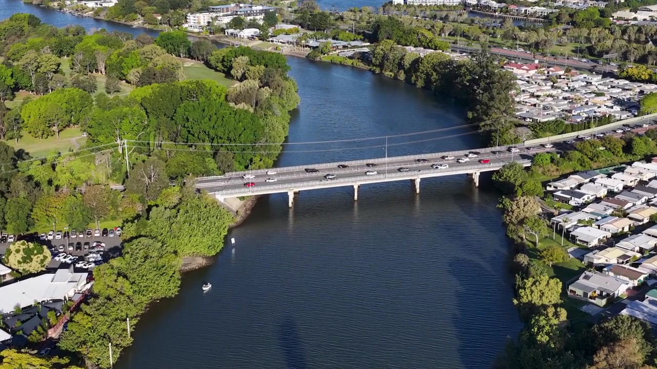 Toma aérea con dron de coches circulando por un puente sobre un río azul