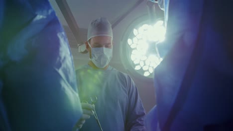 vista de ángulo bajo de un cirujano caucásico que realiza una operación en el teatro de operaciones del hospital