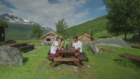 couple enjoying a picnic and apples in a scenic mountain landscape with traditional cabins