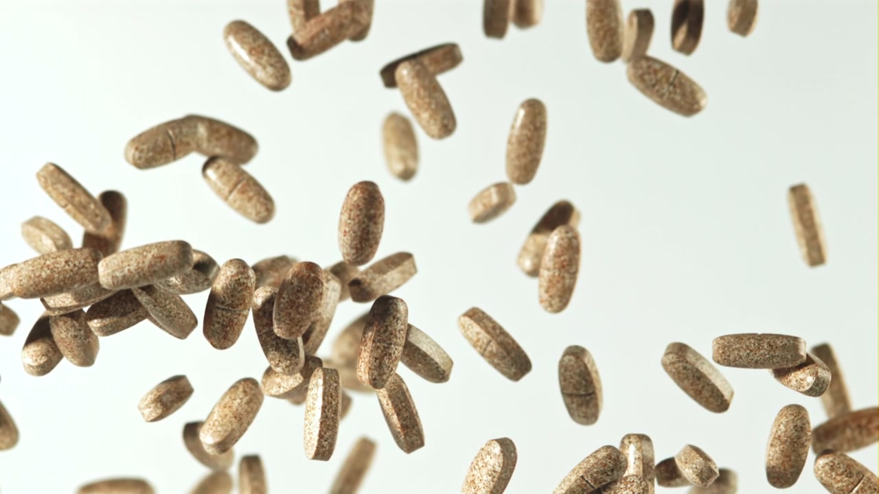 Numerous Brown Pills Floating and Falling on White Background