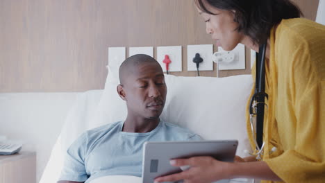 Médico-Con-Tableta-Digital-Visitando-Y-Hablando-Con-Un-Paciente-Masculino-En-La-Cama-De-Un-Hospital