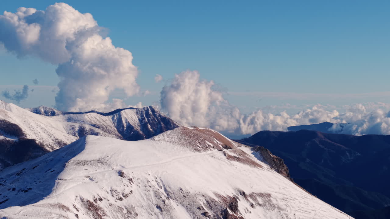 Cime innevate che si ergono sopra le nuvole nelle Alpi italiane, vista aerea da drone