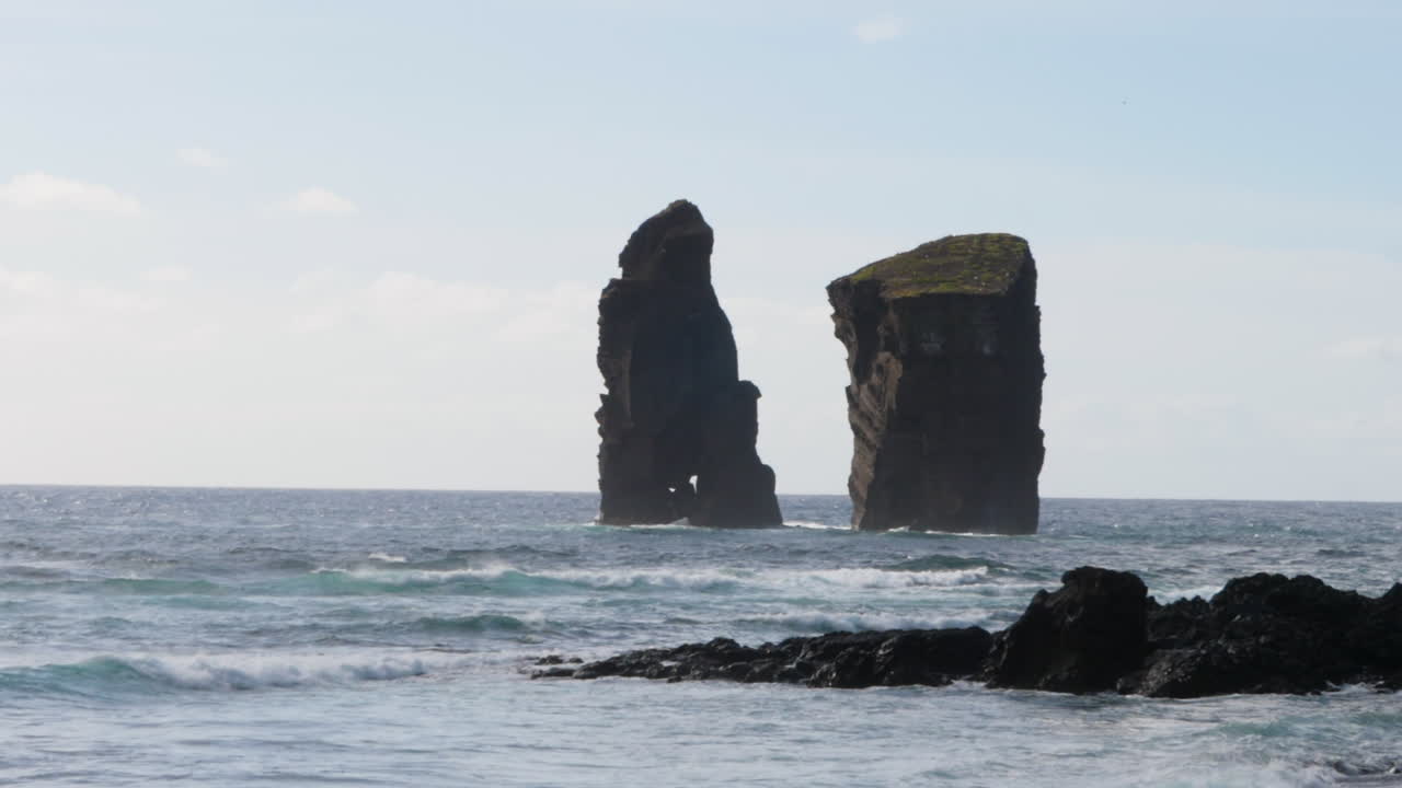 mar tormentoso chocando contra las rocas al atardecer