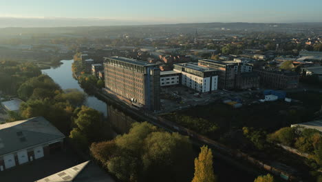 establecimiento de una toma de un antiguo molino industrial convertido en apartamentos en la ciudad de leeds, junto al río aire, con reflejos al amanecer en el oeste de yorkshire, reino unido