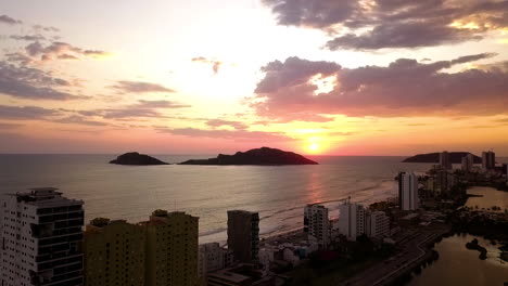 Skyscraper-beach-cityscape-sunset-with-silhouette-of-an-island-against-the-light