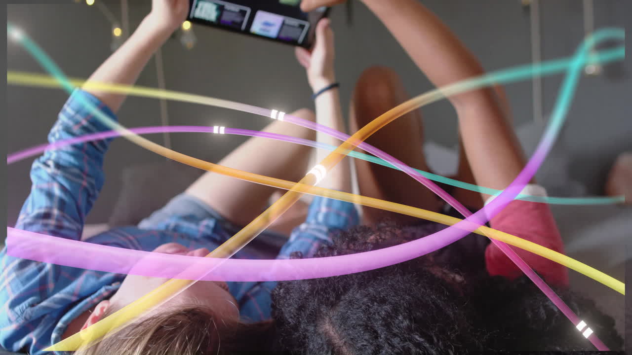 Colorful light trails animation over people lying down and using tablet