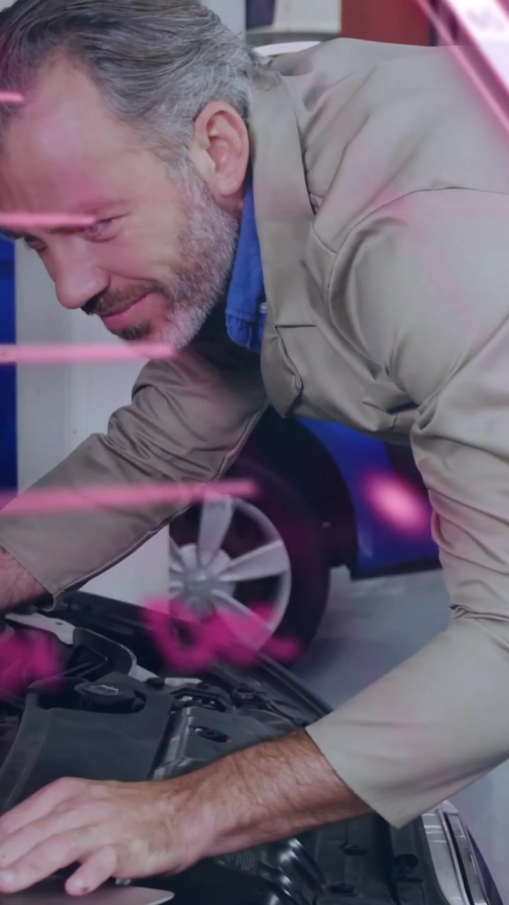 Vertical video: Tech leaning over auto hood open using tablet testing parts pink graphics over him