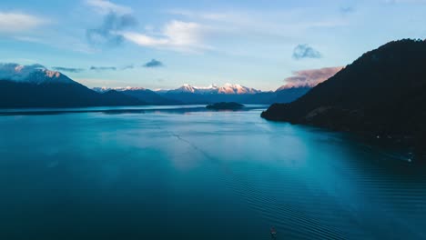 aerial dolly out hyperlapse of lake todos los santos, southern chile with boats sailing, mountains with snowcapped peaks