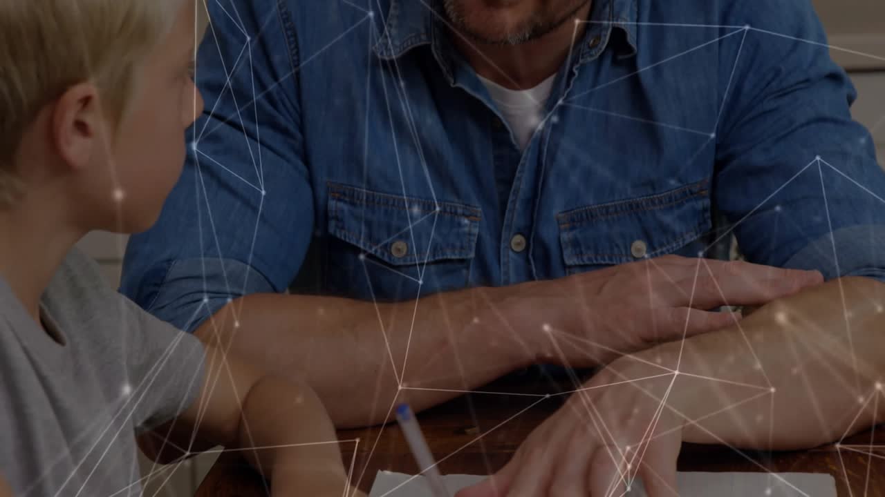 Father pointing at workbook initiating son's writing with blue pencil at wooden table for education