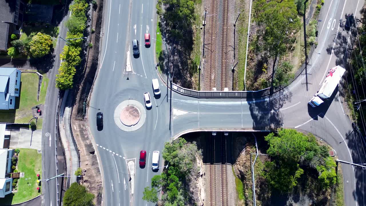 vista del paisaje de automóviles vehículos que conducen alrededor de la rotonda y camión sobre tren ferrocarril puente transporte infraestructura de tráfico ourimbah australia dron aéreo