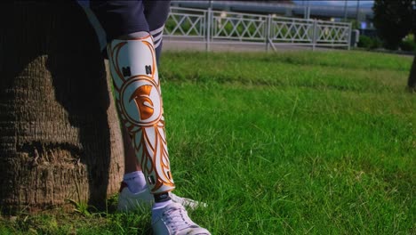 person with a decorative prosthetic leg resting by a tree