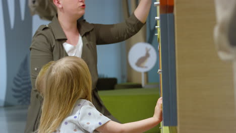 mother playing discovery games with two little children in the museum, side view