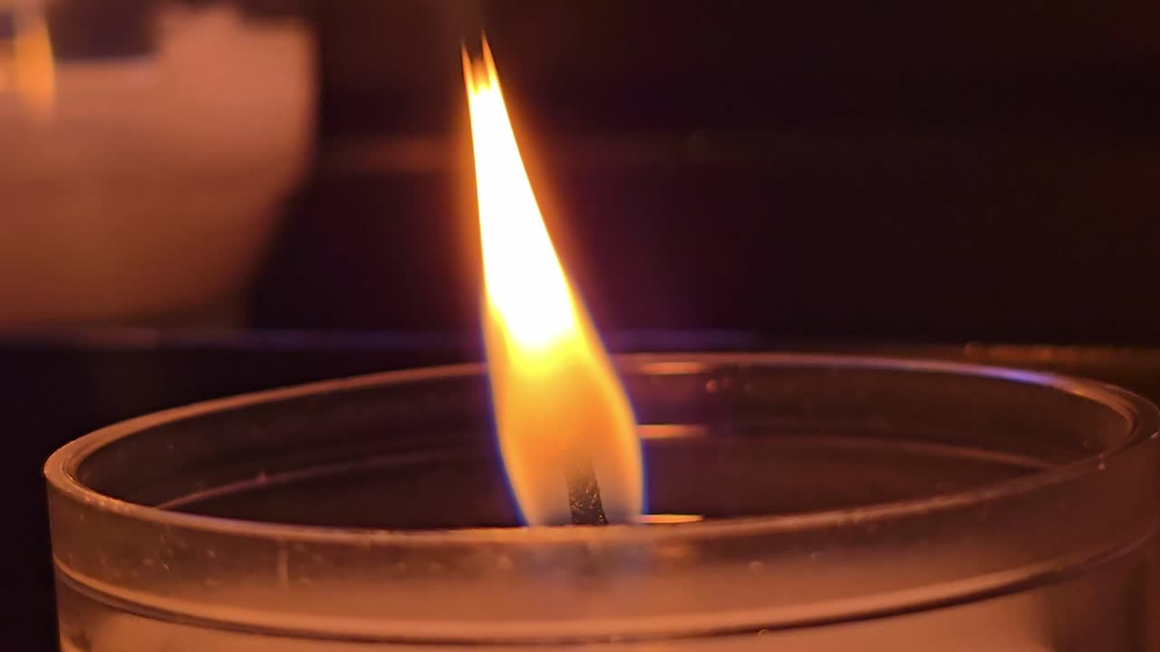 Primo piano di una fiamma di candela che oscilla delicatamente in una luce calda