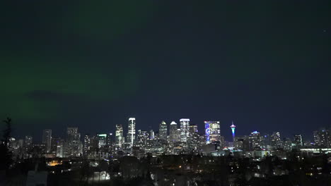 Fascinante-Espectáculo-De-Auroras-Boreales-Bailando-Con-Gracia-Sobre-El-Bullicioso-Horizonte-De-La-Ciudad,-Mostrando-La-Aurora-Boreal,-El-Paisaje-Urbano,-La-Belleza-Celestial-Y-Las-Maravillas-Nocturnas.