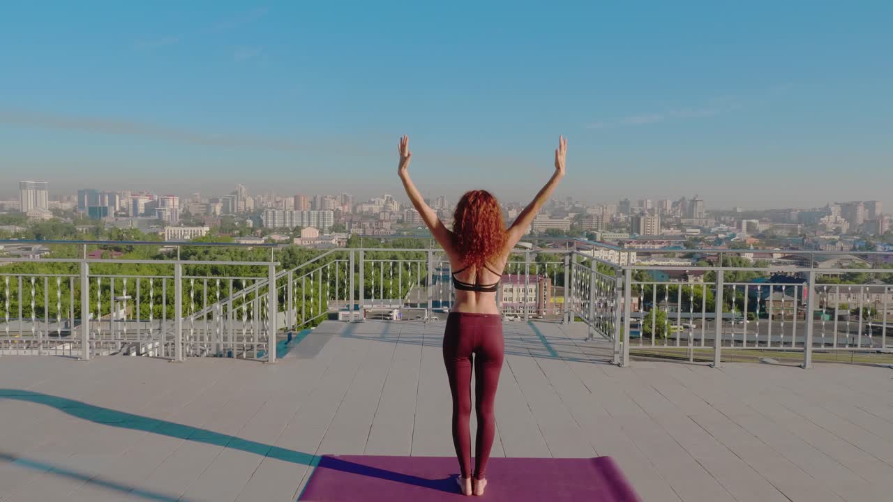 Woman practicing yoga on a rooftop overlooking a city