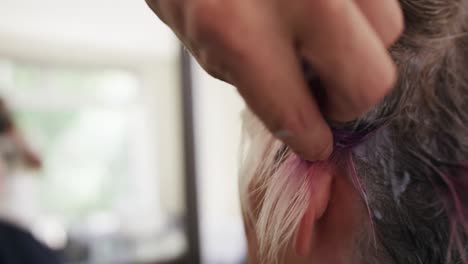 Close-up-view-woman-having-her-hair-styled-by-a-hairdresser