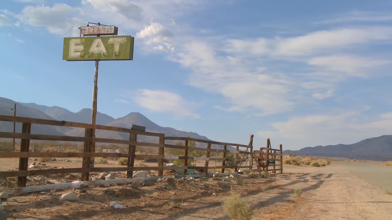 lapso de tiempo y toma de zoom lento de nubes que se deslizan más allá de un letrero que dice comer en un restaurante abandonado
