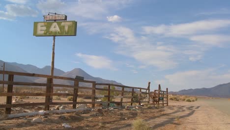 Lapso-De-Tiempo-Y-Disparo-De-Zoom-Lento-De-Nubes-Pasando-Por-Un-Letrero-Que-Dice-Comer-En-Un-Restaurante-Abandonado