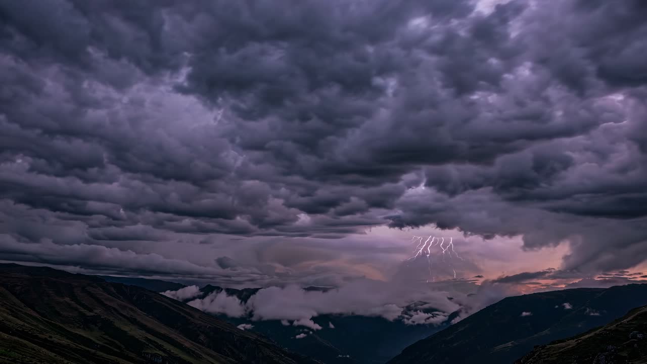 Dramatic landscape video capturing a low-angle view of storm clouds over mountains at sunset