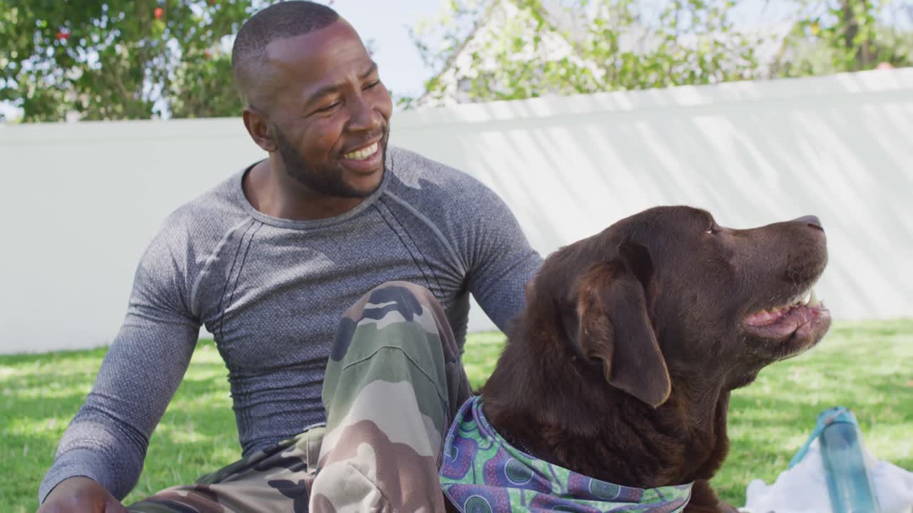 Soldado afro-americano sentado e acariciando seu cachorro no jardim
