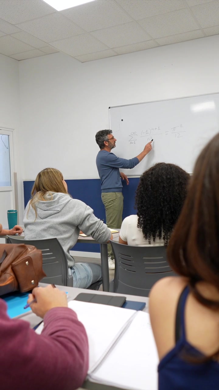 Professore che spiega equazioni matematiche agli studenti in un'aula.