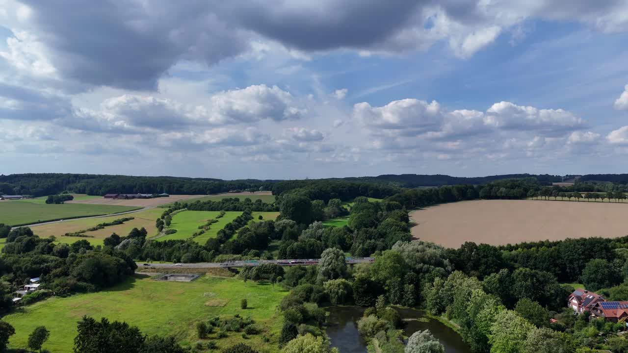 Idyllic landscape of hills with highway at cloudy day. Aerial wide shot. Suburb district with agricultural fields in Pennsylvania. Green forest in America. Summer season