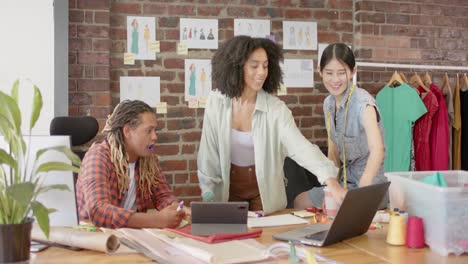 Diverse-creative-women-talking-and-using-laptop-in-creative-office