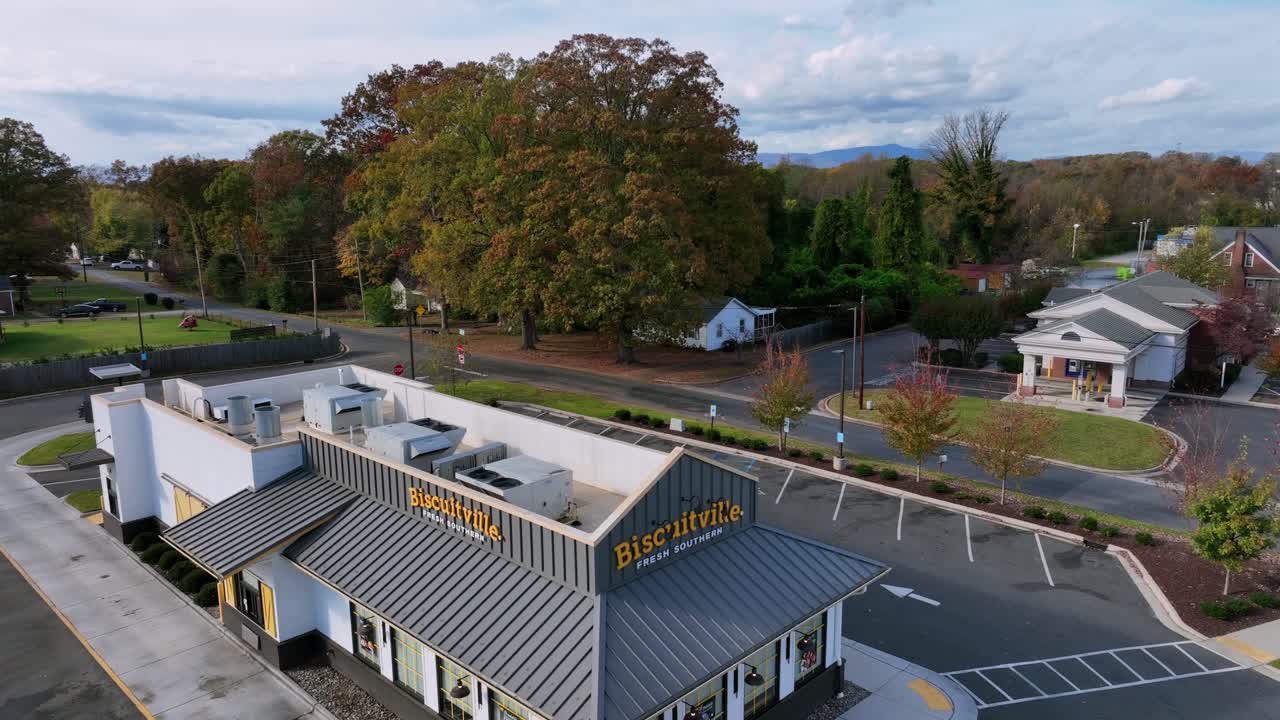 Biscuitville Restaurant with empty parking area in american suburb town. Cloudy day in Autumn season. Rising drone wide shot. Restaurant chain of North Carolina, USA.