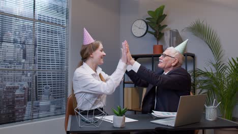 two colleagues celebrating at the office with party hats