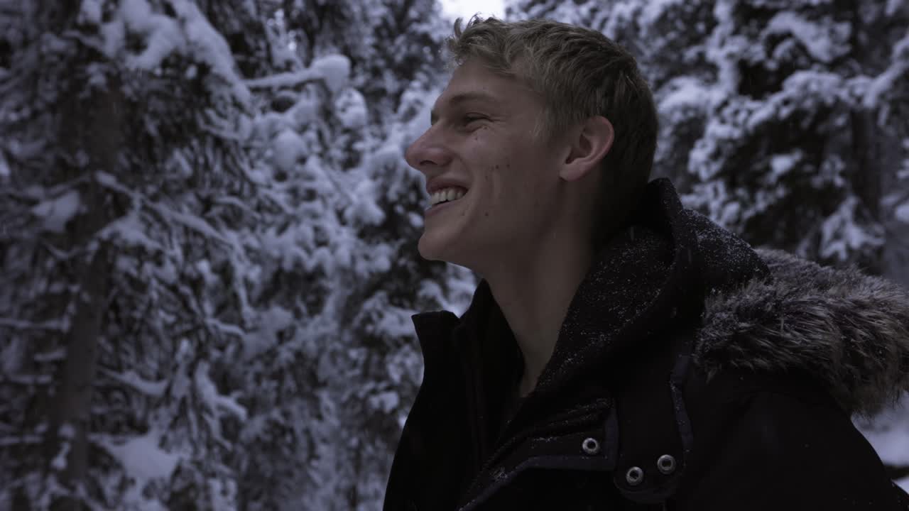 눈 덮인 숲에서 하이킹하는 푹신한 파카를 입은 남자, 4k