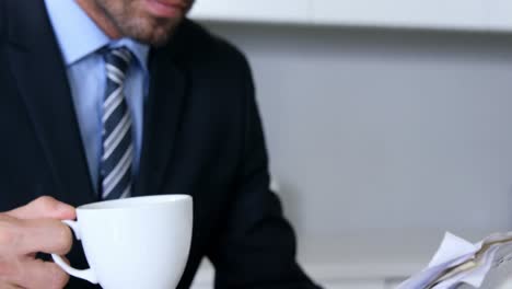 Businessman-reading-documents-while-drinking-coffee