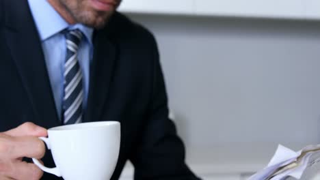 businessman reading documents while drinking coffee