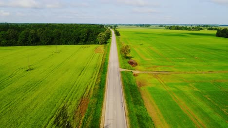 latvian countryside road stretches through vibrant farmland seen from drone