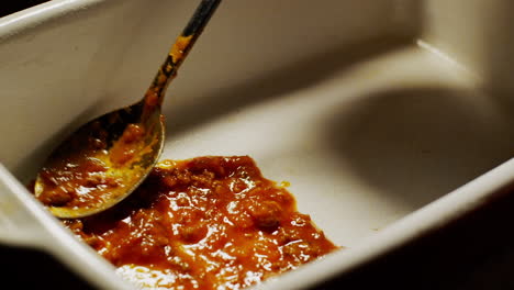 Placing-the-base-layer-of-a-lasagna-inside-a-ceramic-cooking-fret-tray,-close-up