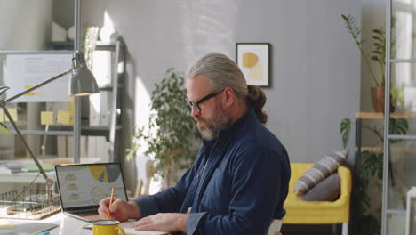 Älterer-Mann,-Der-Sich-Am-Schreibtisch-Im-Büro-Notizen-Macht