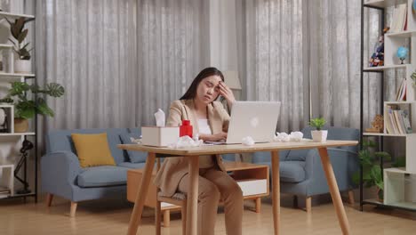 mujer de negocios asiática enferma con dolor de cabeza mientras trabaja con una computadora portátil en la sala de estar en casa